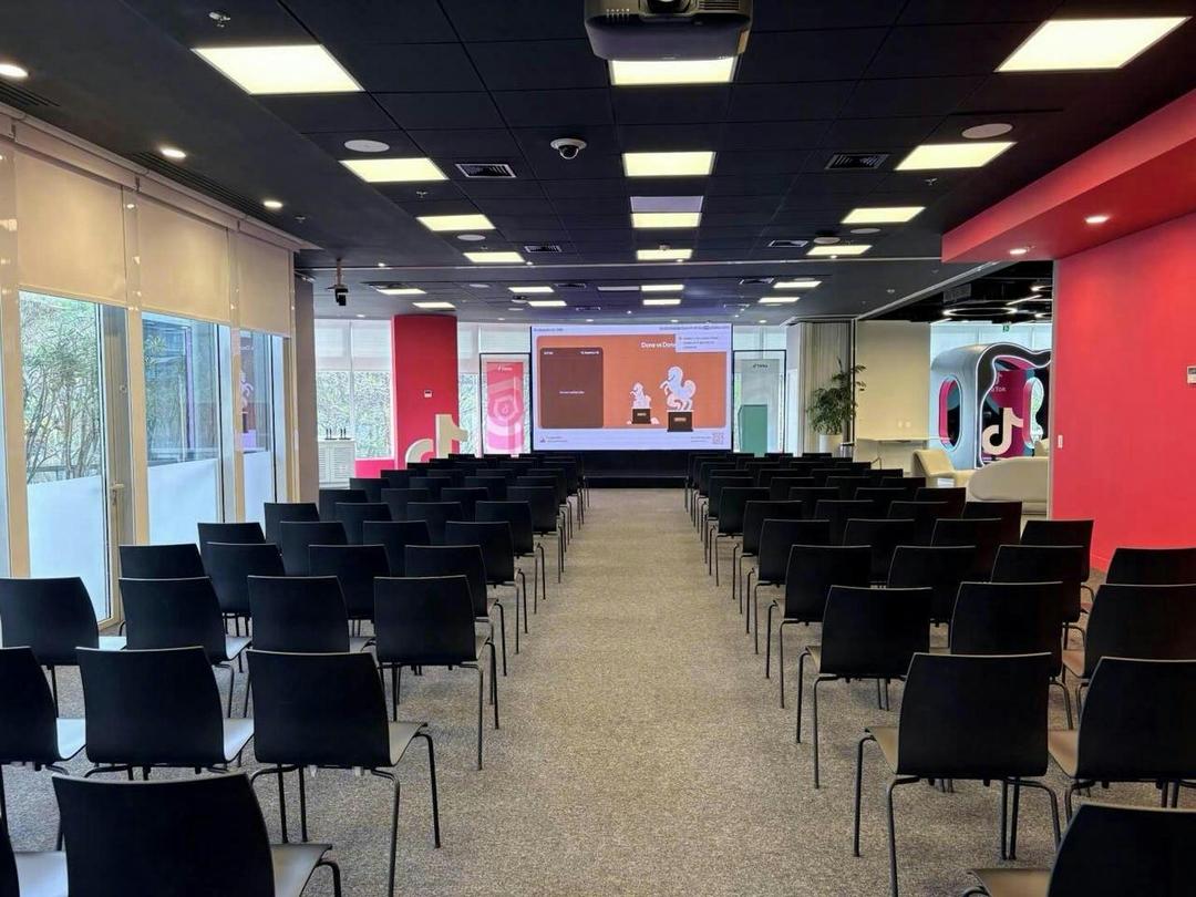 Auditório do escritório do TikTok com telão e cadeiras posicionadas para o evento